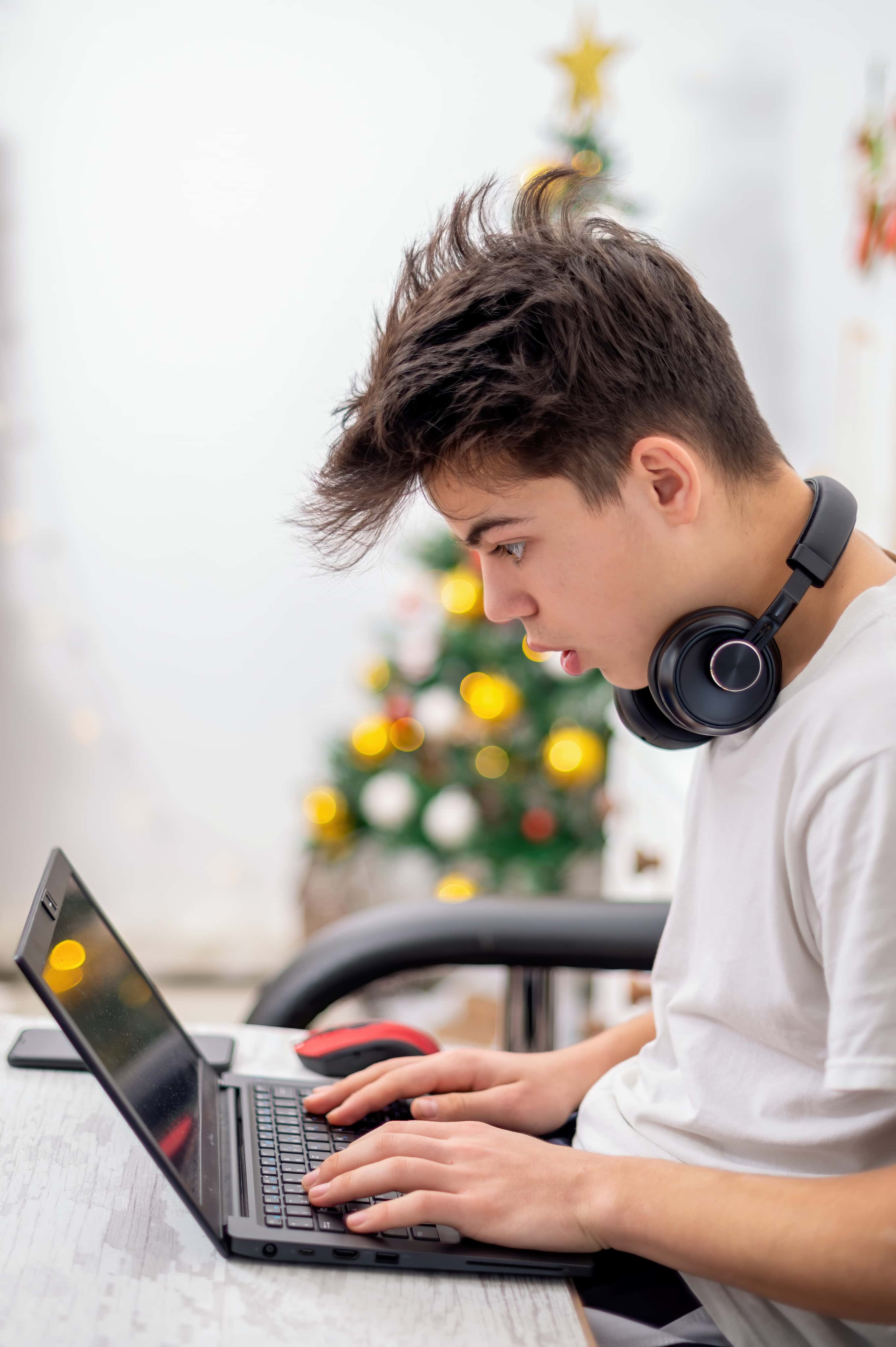 Uczeń szkoły zdalnej pracuje na laptopie w domu podczas nauki programowania online