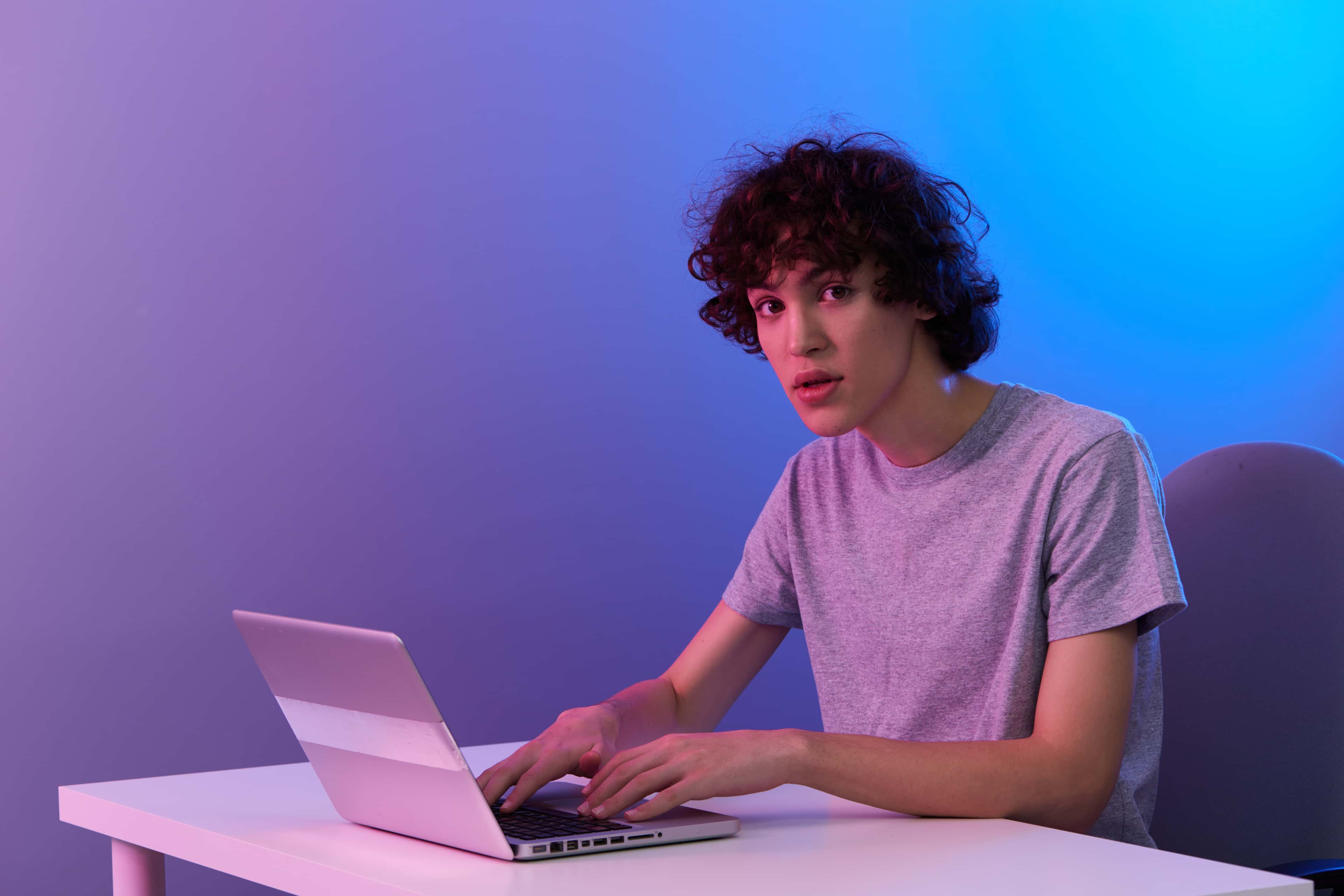 Student technikum online pracuje na laptopie w nowoczesnym oświetleniu neonowym
