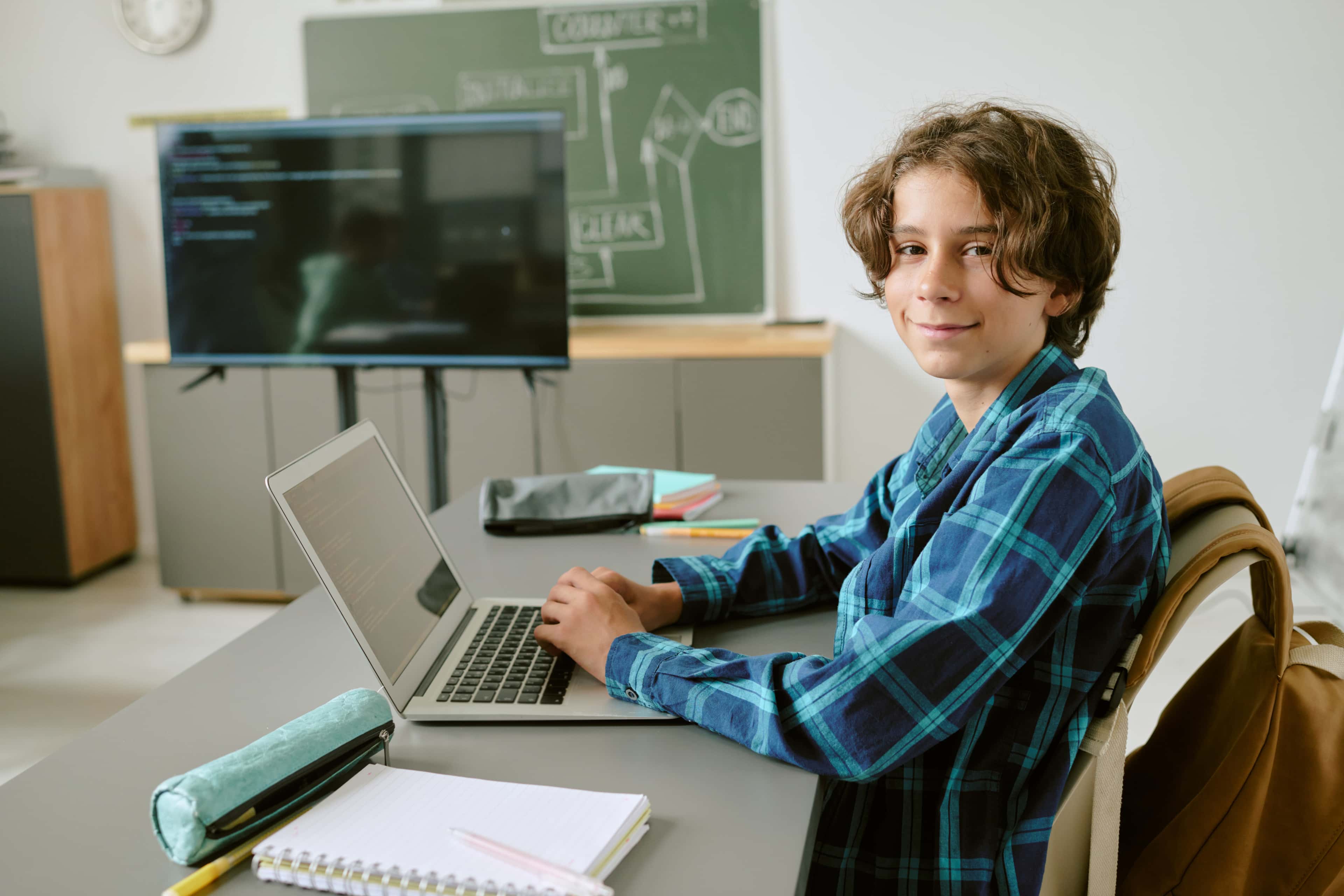 Uczeń szkoły podstawowej na lekcji informatyki uczy się programowania na laptopie