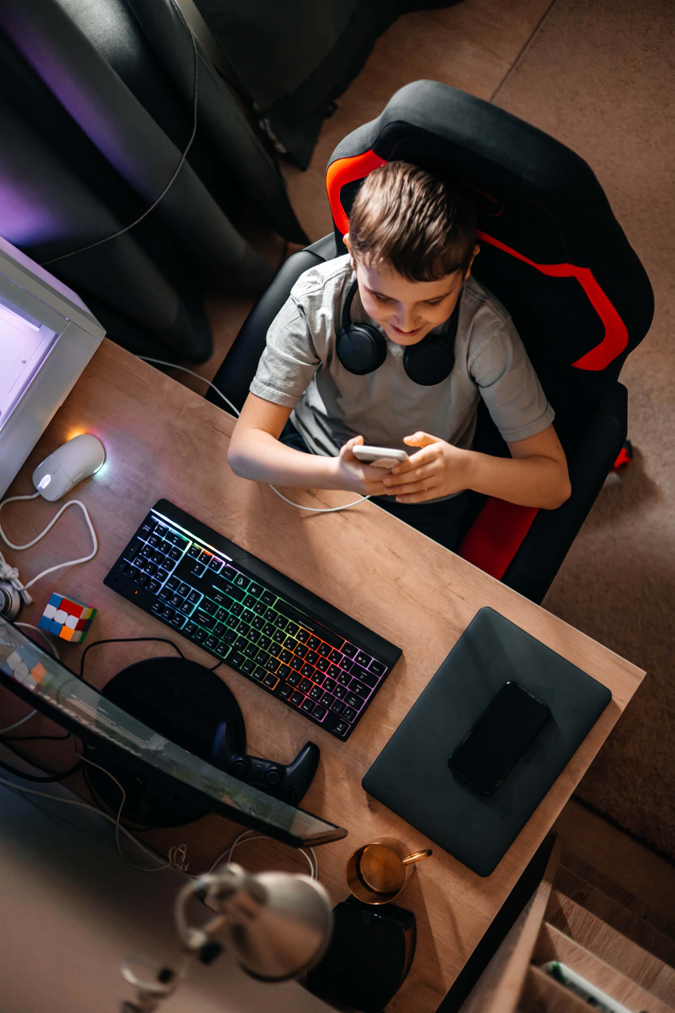 Uczeń przy gamingowym stanowisku komputerowym uczy się programowania zdalnie w domu